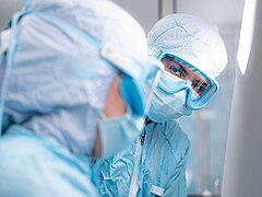 Mitarbeitende in der Sterilherstellung bei der Herstellung individueller Infusionslösungen im Reinraum.
